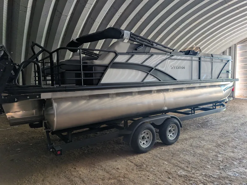 Slide: The Image of A 2026 Sylvan L3 LZ DH pontoon boat on a trailer in a covered area. - 7