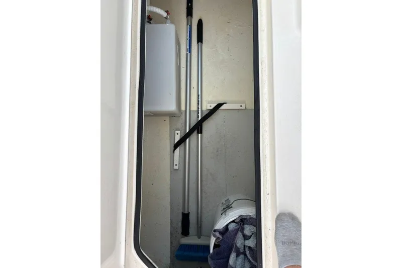 Slide: The Image of Storage compartment in a 2022 Cobia 280 Dual Console boat with cleaning tools. - 25