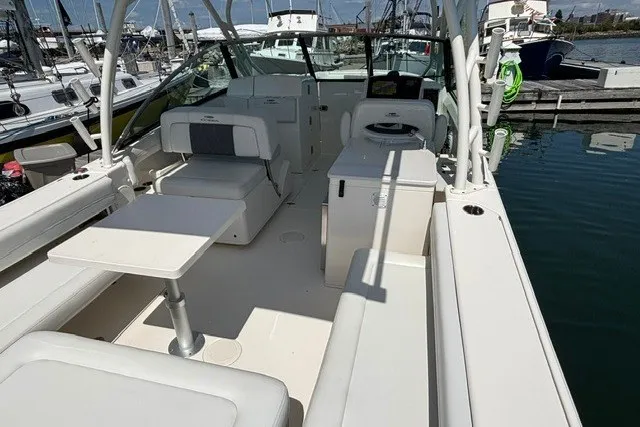 Slide: The Image of 2022 Cobia 280 Dual Console boat interior with seating and table at marina. - 20
