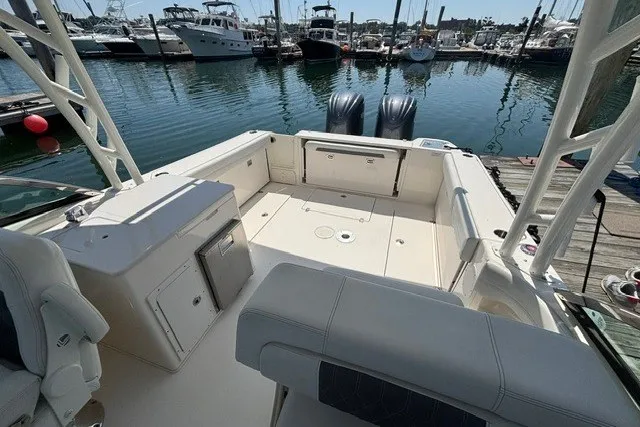 Slide: The Image of 2022 Cobia 280 Dual Console boat interior at marina, showcasing spacious seating and twin engines. - 10