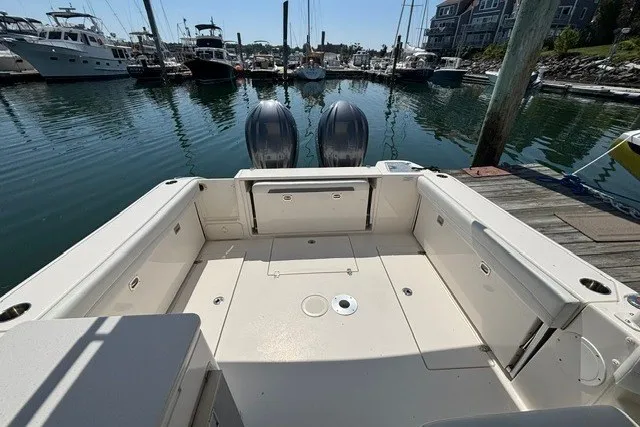 Slide: The Image of 2022 Cobia 280 Dual Console boat docked in a marina, showcasing spacious deck area. - 12