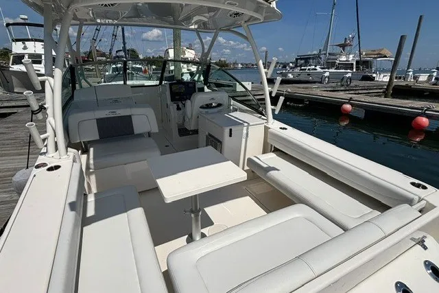 Slide: The Image of 2022 Cobia 280 Dual Console boat interior with seating and table at marina. - 19