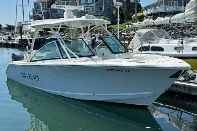 Slide: The Image of 2022 Cobia 280 Dual Console boat docked in a marina, surrounded by other vessels. - 1