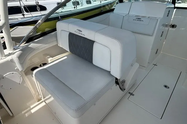 Slide: The Image of 2022 Cobia 280 Dual Console boat interior with white cushioned seating and storage compartments. - 21