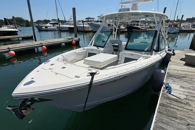 Slide: The Image of 2022 Cobia 280 Dual Console boat docked at a marina with other vessels. - 4
