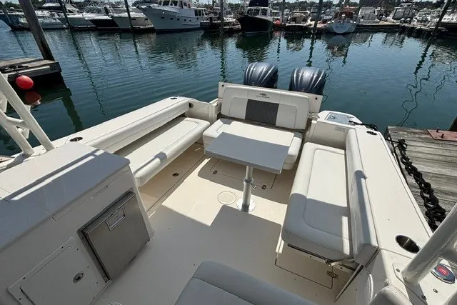 Slide: The Image of 2022 Cobia 280 Dual Console boat interior with seating and table, docked at marina. - 15
