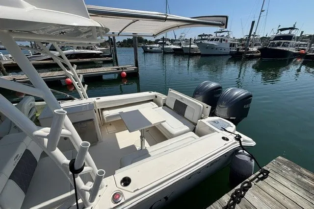Slide: The Image of 2022 Cobia 280 Dual Console boat docked, featuring spacious seating and twin engines. - 16