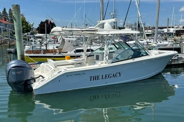 Slide: The Image of 2022 Cobia 280 Dual Console boat named "The Legacy" docked in a marina. - 3