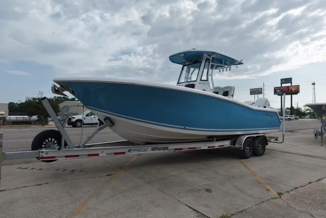Slide: The Image of 2026 Tidewater 272 LXF boat on trailer, blue hull, parked outdoors under cloudy sky. - 2