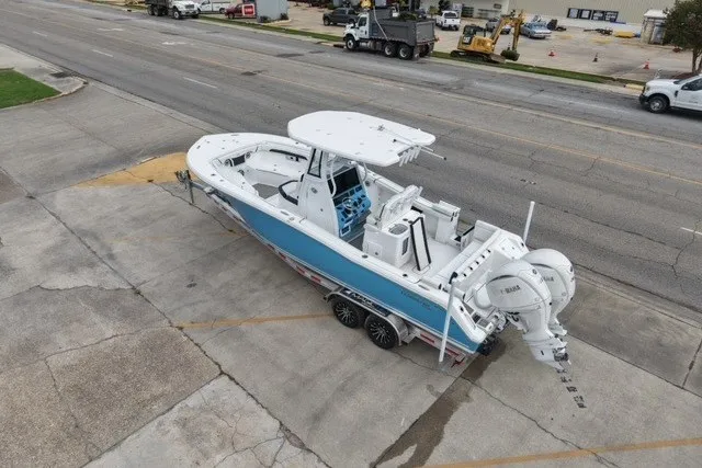 Slide: The Image of 2026 Tidewater 272 LXF boat on trailer, parked on a street, featuring dual outboard engines. - 6