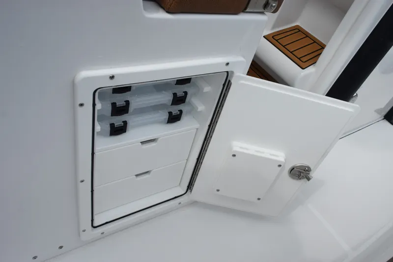 Slide: The Image of Storage compartment on 2027 Sea Hunt Ultra 235SE boat with open door and organized trays. - 20