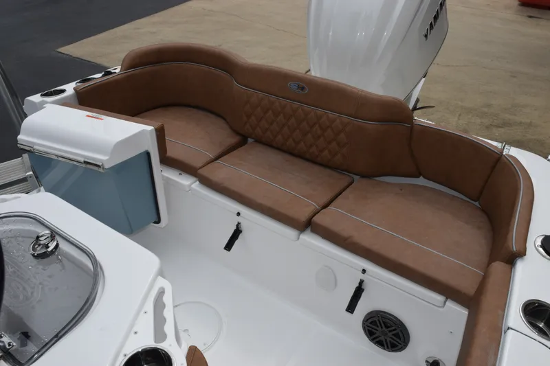 Slide: The Image of 2027 Sea Hunt Ultra 235SE boat interior with brown cushioned seating and modern amenities. - 9