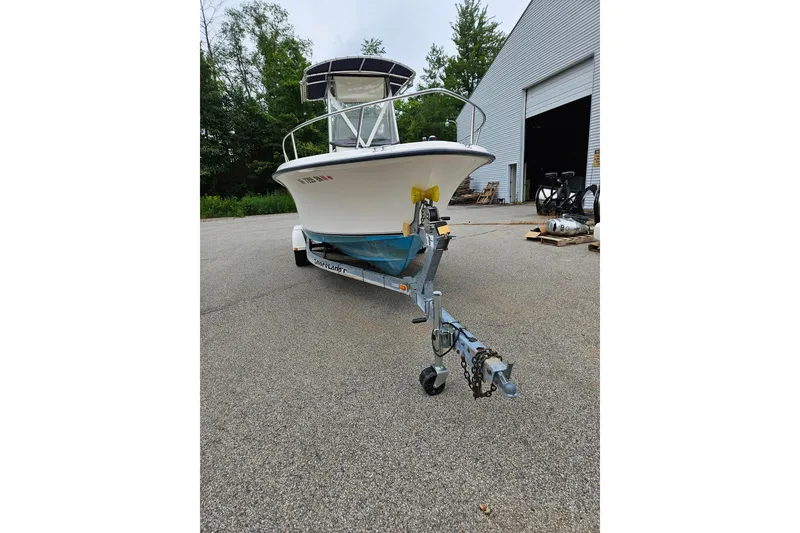 Slide: The Image of 2005 Sea Hunt Triton 232 boat on trailer, parked near a warehouse. - 3