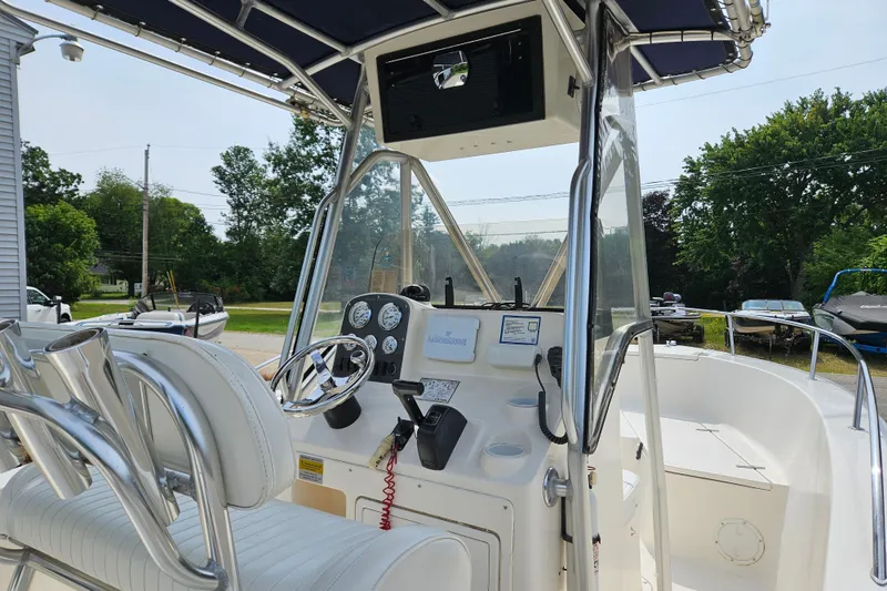 Slide: The Image of 2005 Sea Hunt Triton 232 boat cockpit with steering wheel and gauges, surrounded by lush greenery. - 14