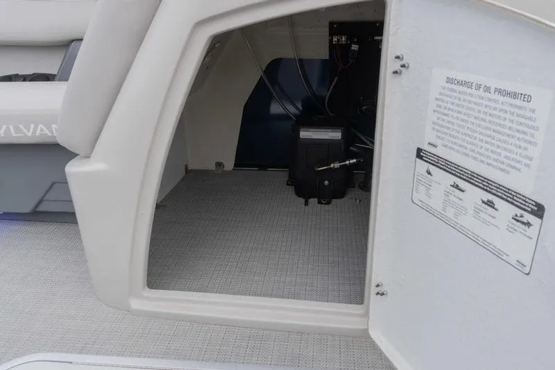 Slide: The Image of Open storage compartment in 2024 Sylvan L5 DLZ boat, showcasing interior details and safety instructions. - 13