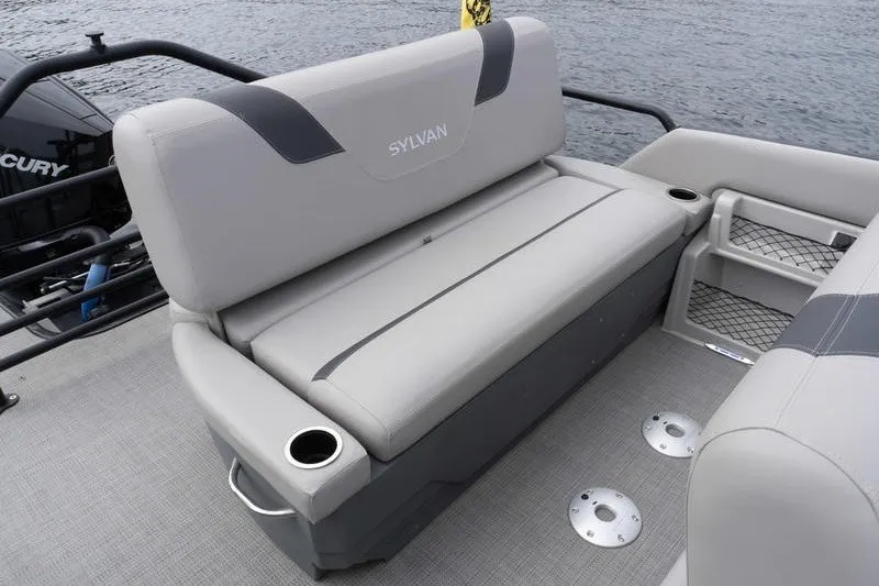 Slide: The Image of 2024 Sylvan L5 DLZ boat interior with gray seating and cup holders on a lake. - 26