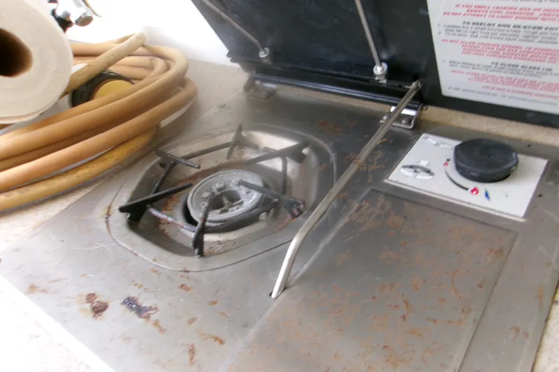 Slide: The Image of Rusty stove on a 2007 Century 2400 Walk-Around boat, with control knob and hose nearby. - 12