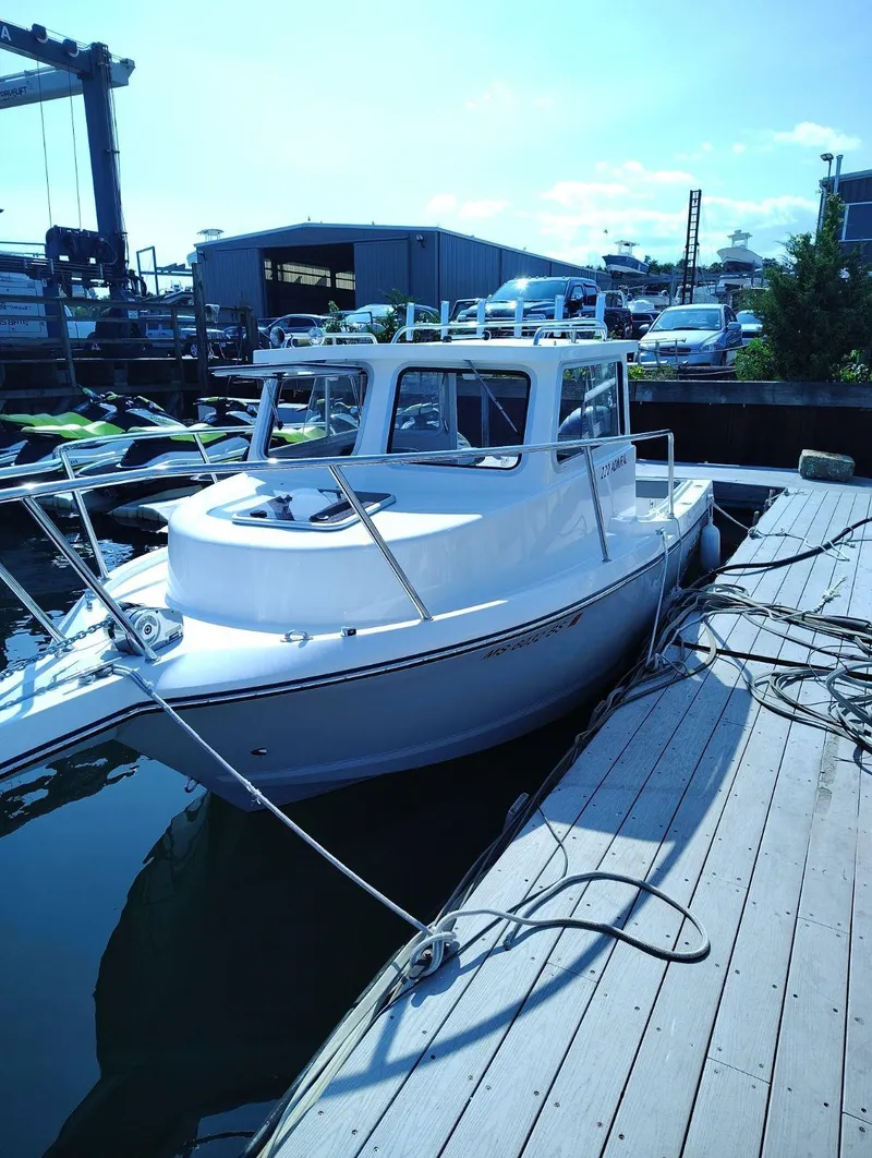 Slide: The Image of A white boat docked, featuring a cabin and open deck, with ropes securing it. - 13