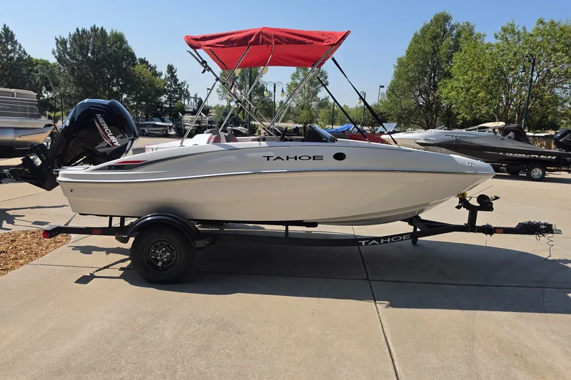 Slide: The Image of 2027 Tahoe T16 boat with red canopy on trailer, parked outdoors. - 5