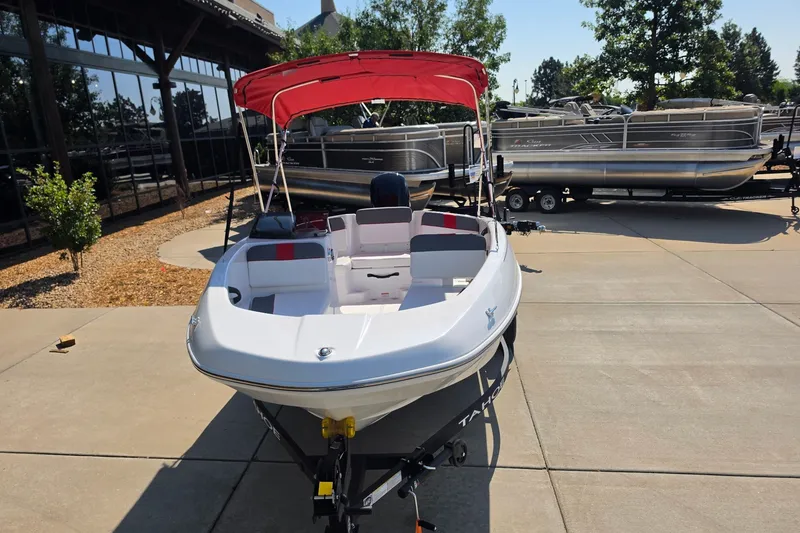 Slide: The Image of 2027 Tahoe T16 boat with red canopy on display outdoors. - 1