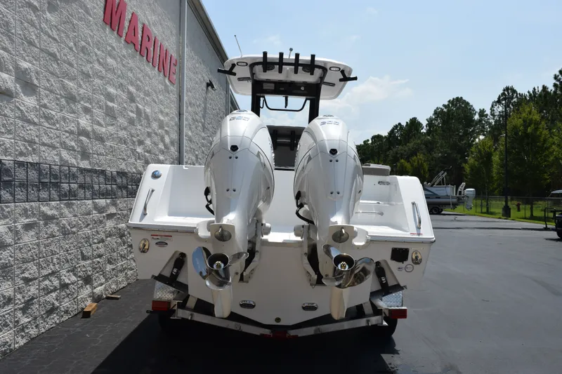 Slide: The Image of 2027 Sea Hunt Gamefish 25 boat with dual outboard motors, parked near a marine building. - 5