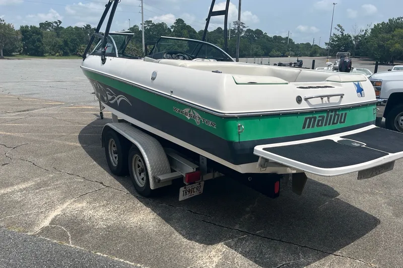 Slide: The Image of 2003 Malibu Wakesetter boat on trailer in parking lot, green and white design. - 4