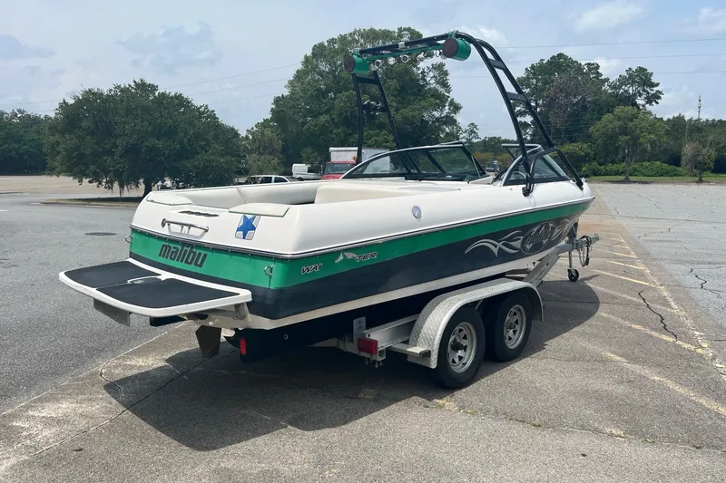 Slide: The Image of 2003 Malibu Wakesetter boat on trailer in parking lot, green and white design. - 6