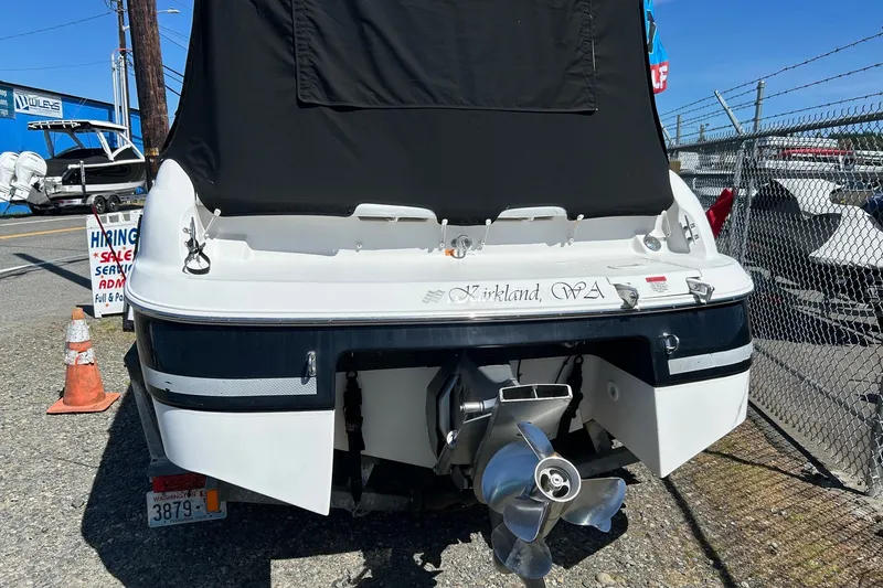 Slide: The Image of 2002 Four Winns 225 Sundowner boat, rear view, parked outdoors with cover and visible propeller. - 2