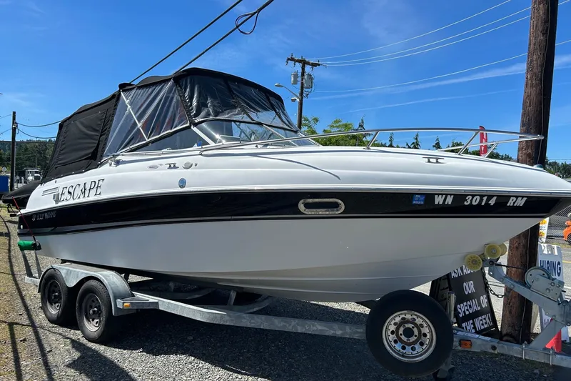 Slide: The Image of 2002 Four Winns 225 Sundowner boat on trailer, featuring black canopy and sleek design. - 1