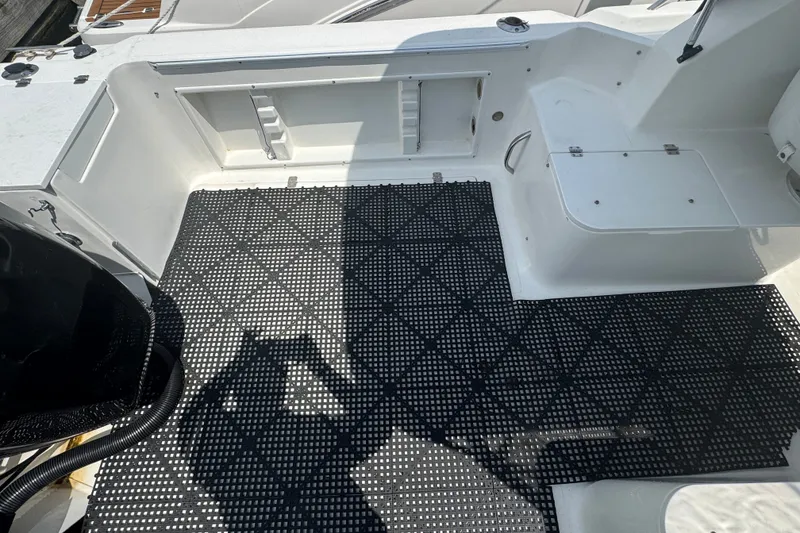 Slide: The Image of 2002 Wellcraft 220 Coastal boat interior with black grid flooring and storage compartments. - 6
