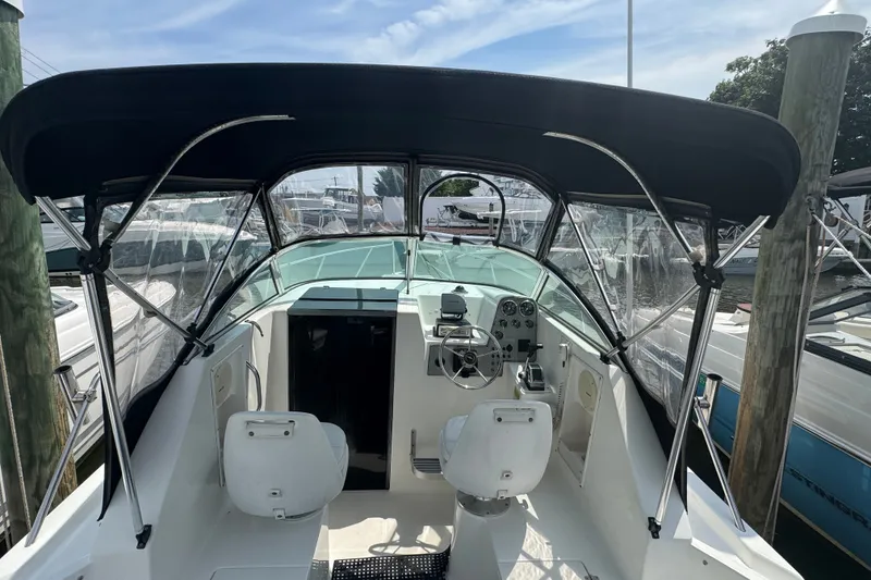 Slide: The Image of 2002 Wellcraft 220 Coastal boat interior with canopy, steering wheel, and seating at dock. - 7