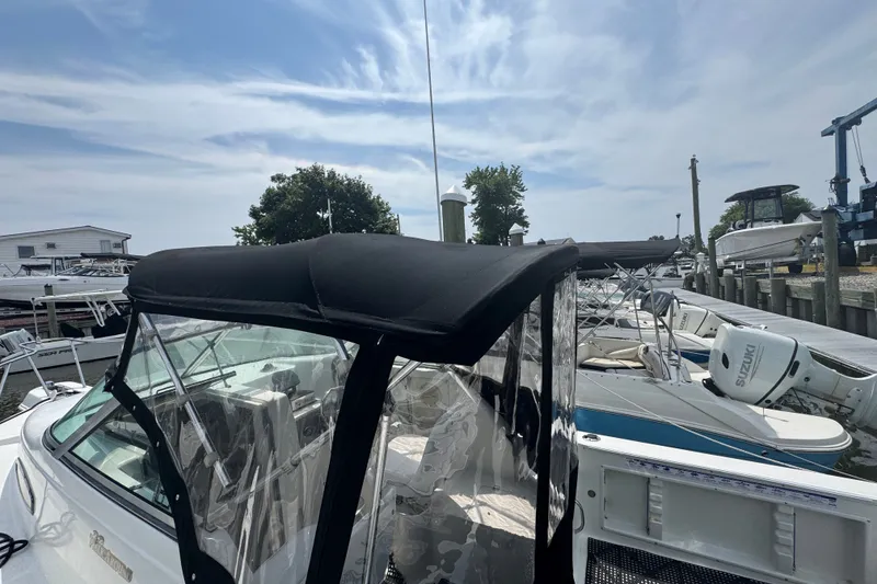 Slide: The Image of 2002 Wellcraft 220 Coastal boat docked, featuring a black canopy and clear side panels. - 15