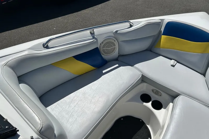 Slide: The Image of 2001 Tige 22i boat interior with white, blue, and yellow seating, featuring cup holders. - 12