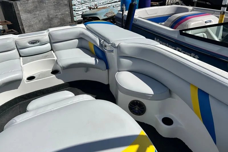 Slide: The Image of 2001 Tige 22i boat interior with white seating and blue-yellow accents. - 20