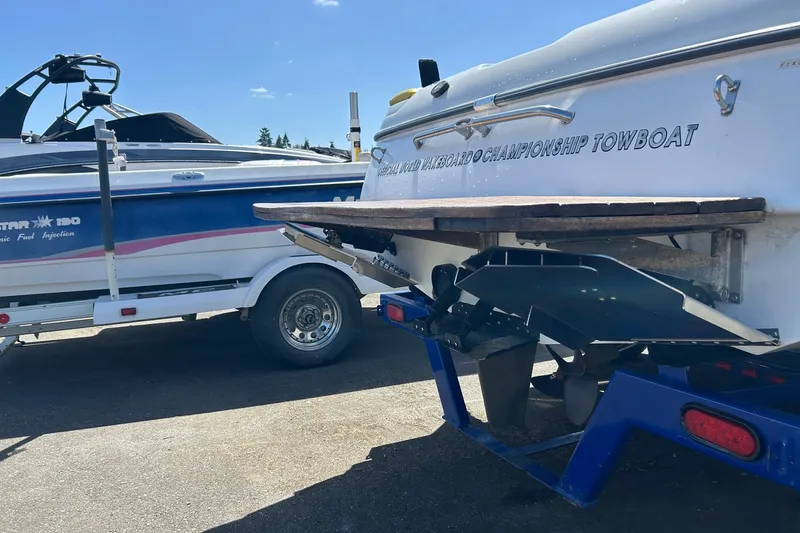 Slide: The Image of 2001 Tige 22i towboat on trailer, parked beside another boat under clear blue sky. - 21