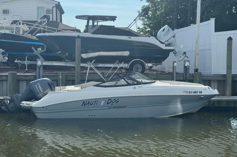 The Image of 2021 Stingray 214 LR boat docked, featuring "Nauti Dog" name and Yamaha outboard motor. - 1