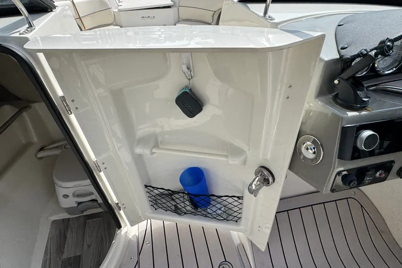 Slide: The Image of 2021 Stingray 214 LR boat interior storage compartment with key and blue cup. - 14