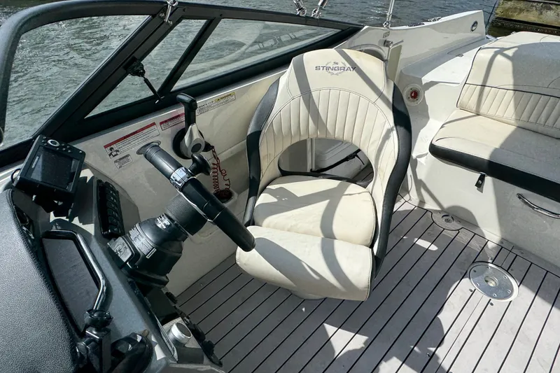 Slide: The Image of 2021 Stingray 214 LR boat interior with steering wheel and seating, on water. - 21
