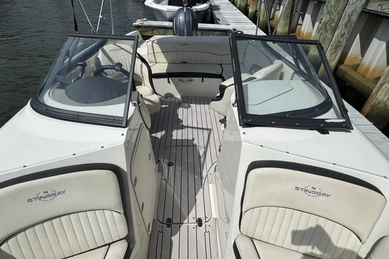 Slide: The Image of 2021 Stingray 214 LR boat interior with seating and steering wheel, docked by the water. - 19