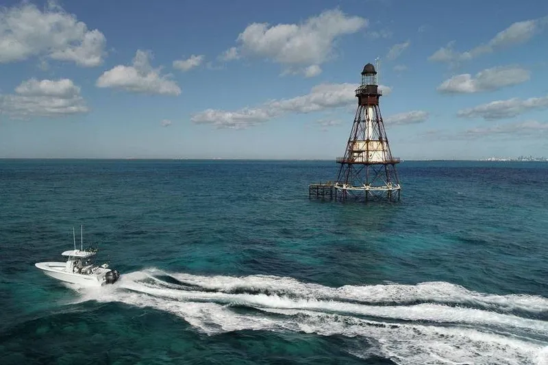 Slide: The Image of A 2026 Contender 25 Tournament boat cruising near an offshore lighthouse in clear blue waters. - 8