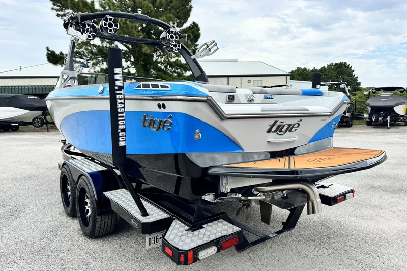 Slide: The Image of 2017 Tigé R23 boat on trailer, blue and white design, parked outdoors. - 6
