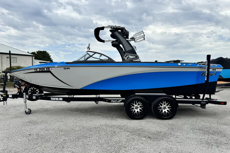 Slide: The Image of 2017 Tigé R23 boat on trailer, blue and white design, parked outdoors. - 7