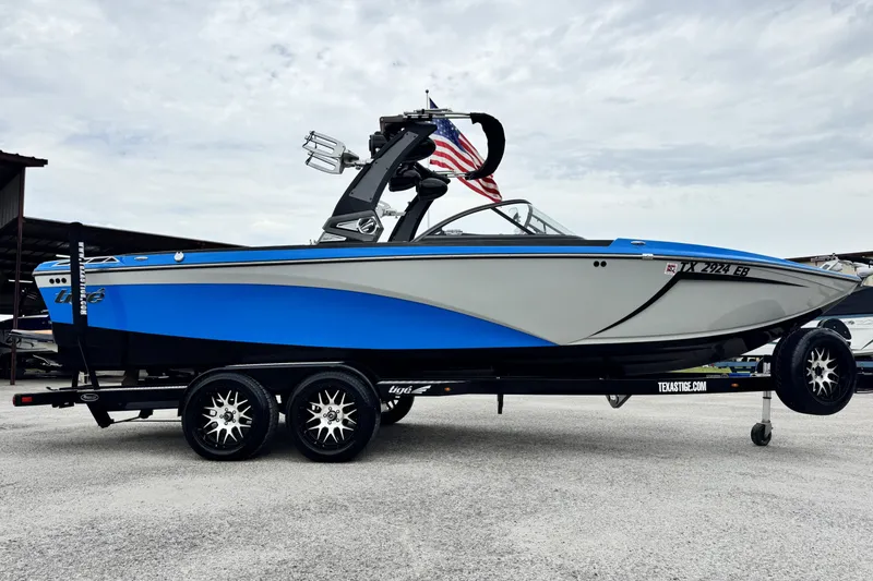 Slide: The Image of 2017 Tigé R23 boat in blue and gray on a trailer with American flag. - 3
