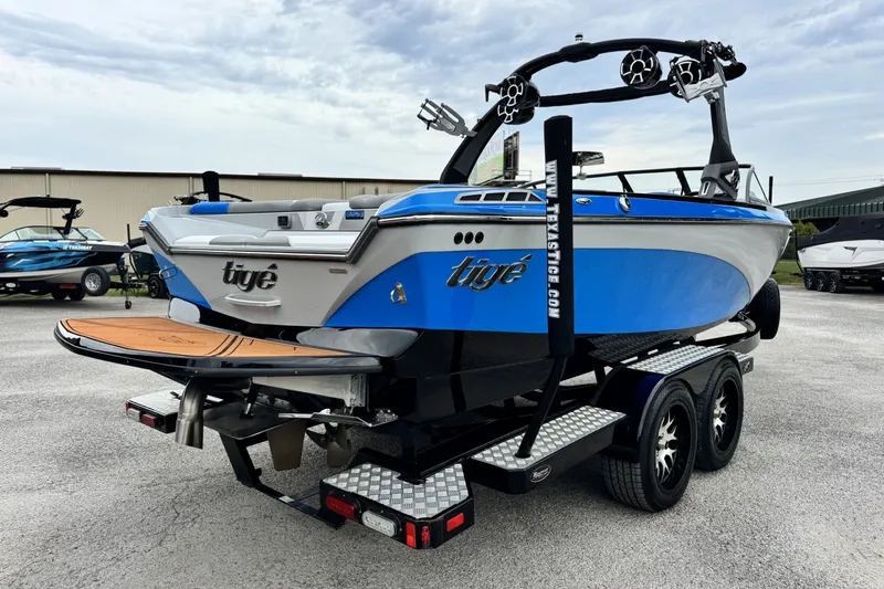 Slide: The Image of 2017 Tigé R23 boat on trailer, blue and white design, parked outdoors. - 4