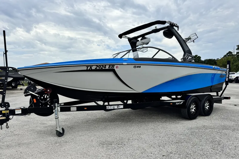 Slide: The Image of 2017 Tigé R23 boat on trailer, blue and white design, parked outdoors. - 8