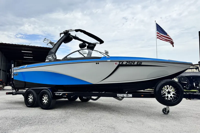 The Image of 2017 Tigé R23 boat on trailer, blue and white design, American flag in background. - 0
