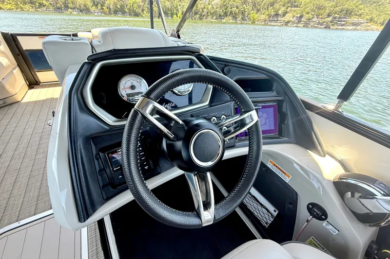 Slide: The Image of 2019 Barletta L23QC SS boat dashboard with steering wheel and control panel on a lake. - 25