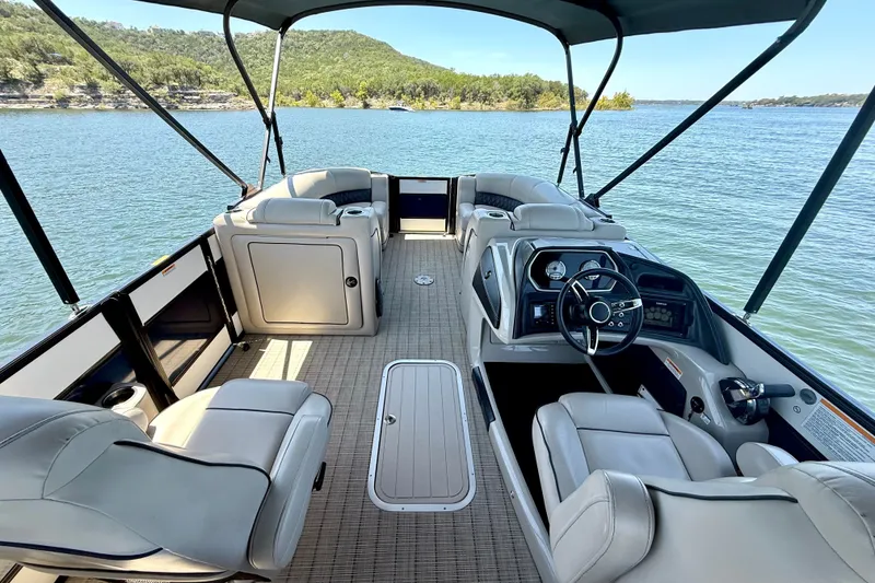Slide: The Image of 2019 Barletta L23QC SS pontoon boat interior with steering console, seating, and lake view. - 19