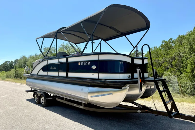 Slide: The Image of 2019 Barletta L23QC SS pontoon boat on trailer, parked roadside under clear sky. - 14