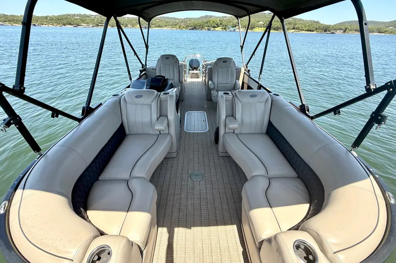 Slide: The Image of 2019 Barletta L23QC SS pontoon boat interior with plush seating on a serene lake. - 17